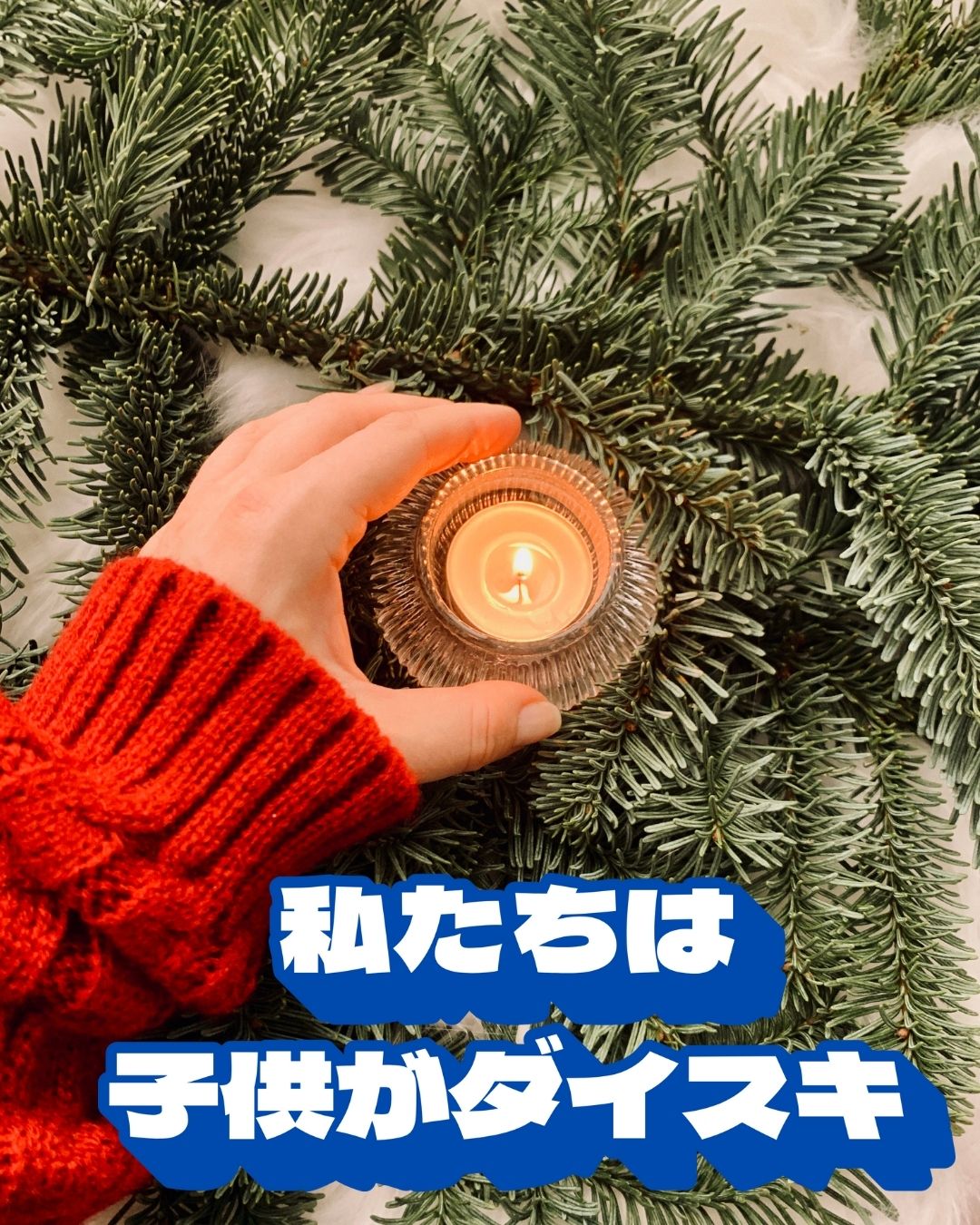 赤いニットを着た手が小さなキャンドルをそっと持ち、周囲をモミの木の枝が囲んでいる冬らしい温かい雰囲気の写真。画像には「私たちは子供がダイスキ」というテキストが配置されている。